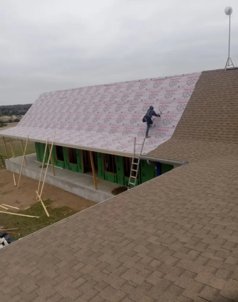 Worker preparing underlayment for a metal roof installation in Johnson Lane